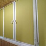 Лаймові рулонні штори встановлені на балконі з обшивкою з вагонки