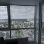 Белые горизонтальные жалюзи на струне, установленные на панорамное окно с отличным видом